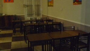 A dining area with multiple tables and chairs, a tiled floor, and artwork on the walls. - Hotel San Martin (Buenos Aires)