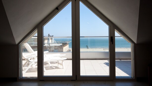 A room with a large window overlooking a beach.