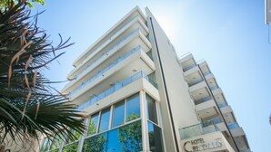 A modern hotel with multiple floors, large windows, and a clear view of the sky.