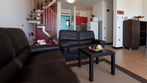 A modern living room with a sofa, a coffee table, and a staircase leading to a kitchen area.