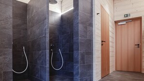 Une salle de bain moderne avec des carreaux de couleur sombre, des murs en bois et un espace douche.