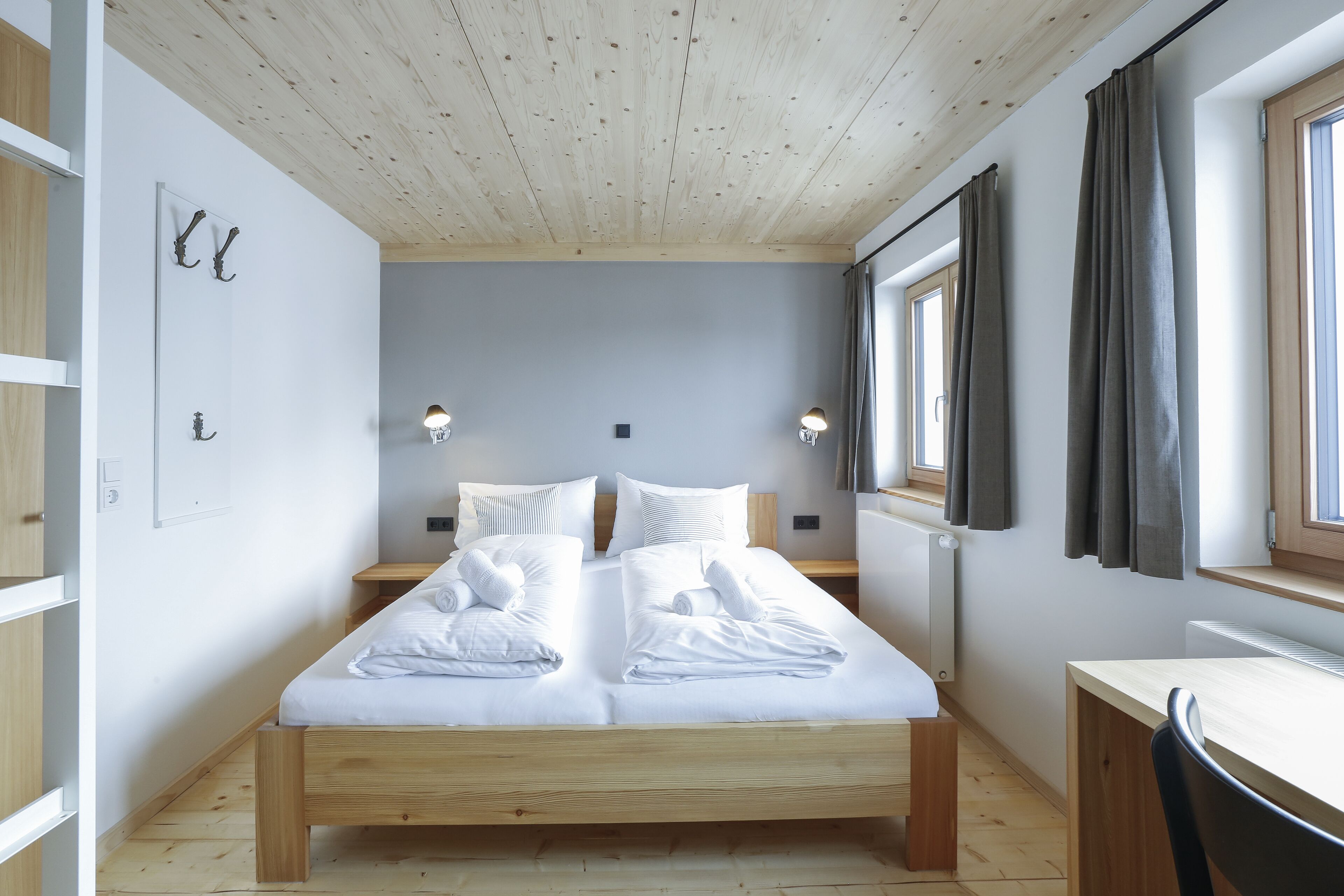 A modern bedroom with a wooden bed, bedside tables, and a desk.