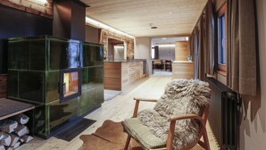 Un salon moderne avec une cheminée, des meubles en bois et une vue sur la cuisine et l’espace repas.