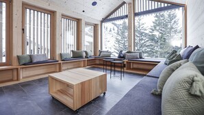 Un intérieur moderne avec des poutres en bois, de grandes fenêtres et des coins salon intégrés.