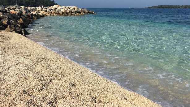 A pebble beach with clear water and a rocky shoreline. - Comfortable apartment near the Hidrobaza beach (Pula)