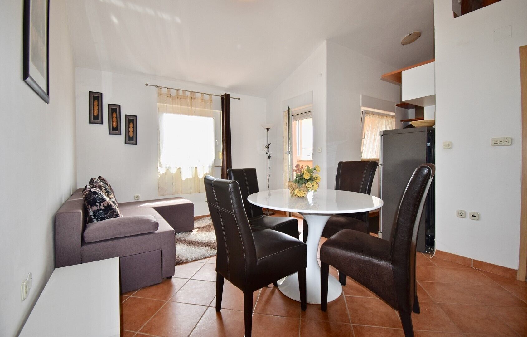 Ett kompakt bostadsutrymme med en matplats, en soffa och ett litet kök.