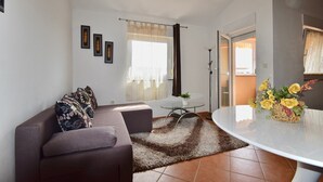 A living room with a sofa, a small round table, and a glass coffee table. - Comfortable apartment near the Hidrobaza beach (Pula)