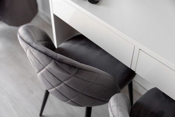 A modern chair with a unique design, positioned next to a white wall and a dark floor. - Wola Chic Grey Studio (Warsaw)
