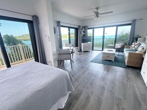 Una habitación amplia con balcón, cama, sofá y televisor.