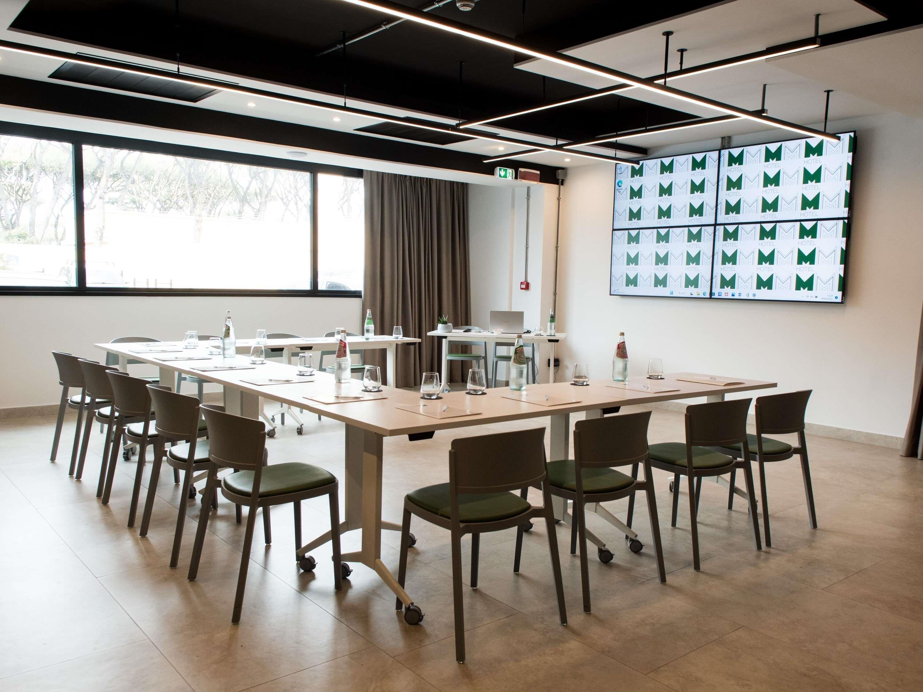 Une salle de conférence avec une longue table, des chaises et une grande fenêtre.
