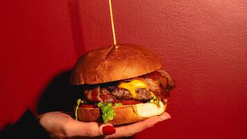 A hand holding a burger with a toothpick.
