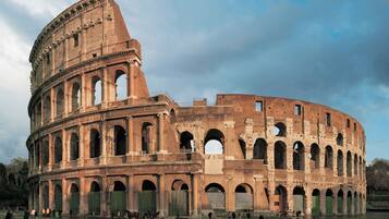 Um grande anfiteatro histórico com vários níveis de arcos e uma área central aberta.