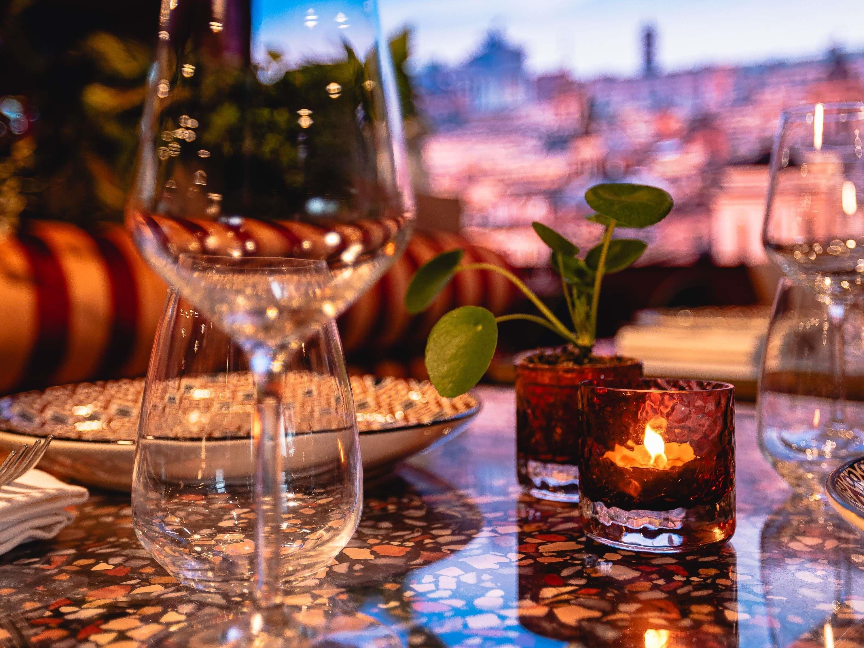 Une table avec un verre d’eau, un verre de vin et deux verres avec une bougie.