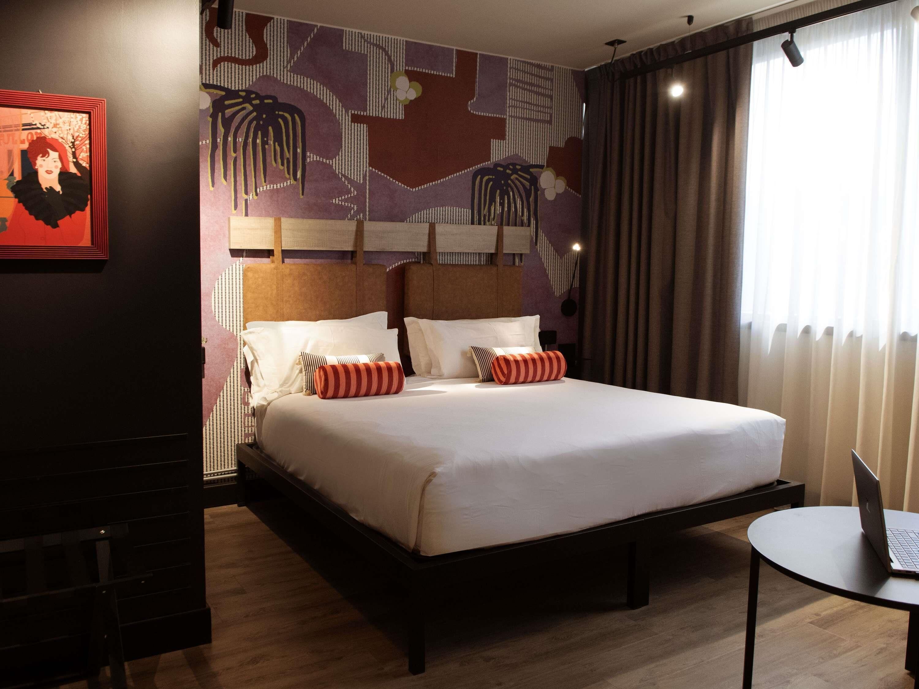 Habitación de hotel con una cama grande, un escritorio y una computadora portátil.