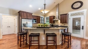 A kitchen with a central island, wooden cabinets, stainless steel appliances, and a clock on the wall. - Come have fun in the sun on the Tennessee River with a private dock (Loudon)
