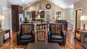 A spacious living room with two leather armchairs, a coffee table, and a kitchen in the background. - Come have fun in the sun on the Tennessee River with a private dock (Loudon)