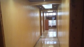 A corridor with wooden walls and a shiny tiled floor, leading to a bright area with windows.
