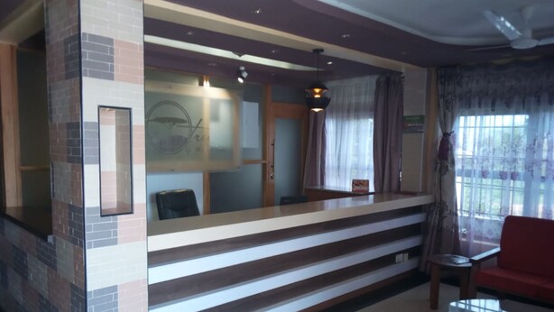 A reception area with a counter, a chair, and a window with curtains.