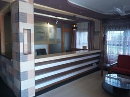 Uma área de recepção com balcão, uma cadeira e janela com cortinas.