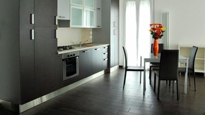 Una cocina moderna con armarios oscuros, una estufa y un comedor con sillas y una mesa.
