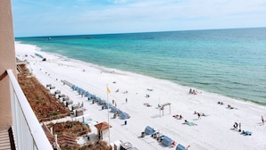 A beach with white sand, a pier in the distance, and beach umbrellas. - Amazing View - 6th Floor Gulf Front Condo - Close to Pier Park (Panama City Beach)