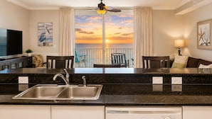 A kitchen with a sink, a ceiling fan, and a view of the ocean at sunset. - Amazing View - 6th Floor Gulf Front Condo - Close to Pier Park (Panama City Beach)