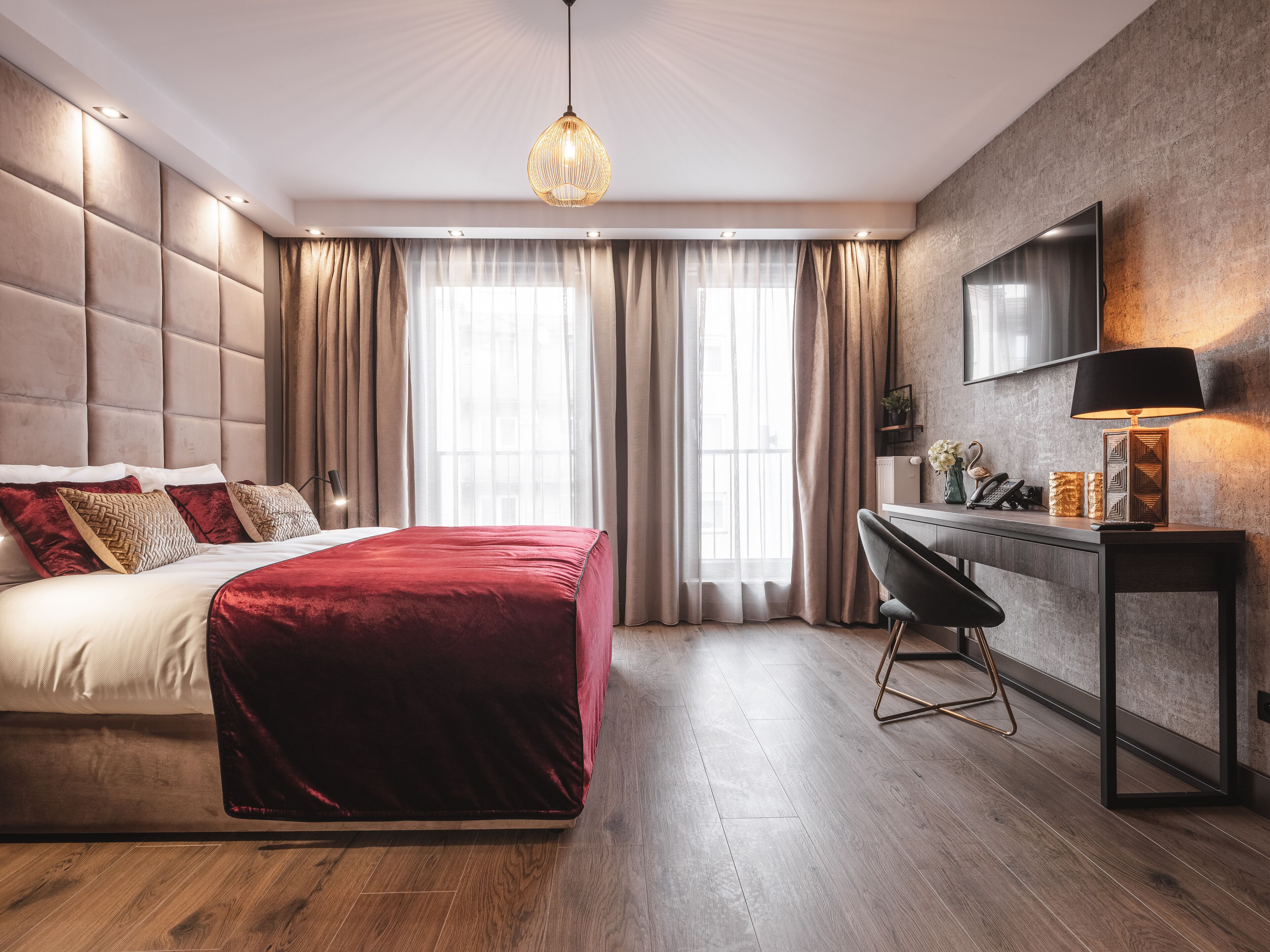 A modern bedroom with a large bed, a desk, and a TV.