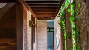 A corridor with wooden beams, brick walls, and a tiled floor. - Pousada Albergue da Jangada (São Miguel do Gostoso)
