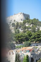 Un castillo de piedra histórico sobre una colina, rodeado de árboles y edificios tradicionales.