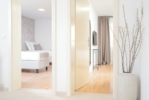 Una habitación de hotel con una cama, televisor, cortina y un florero con ramas.