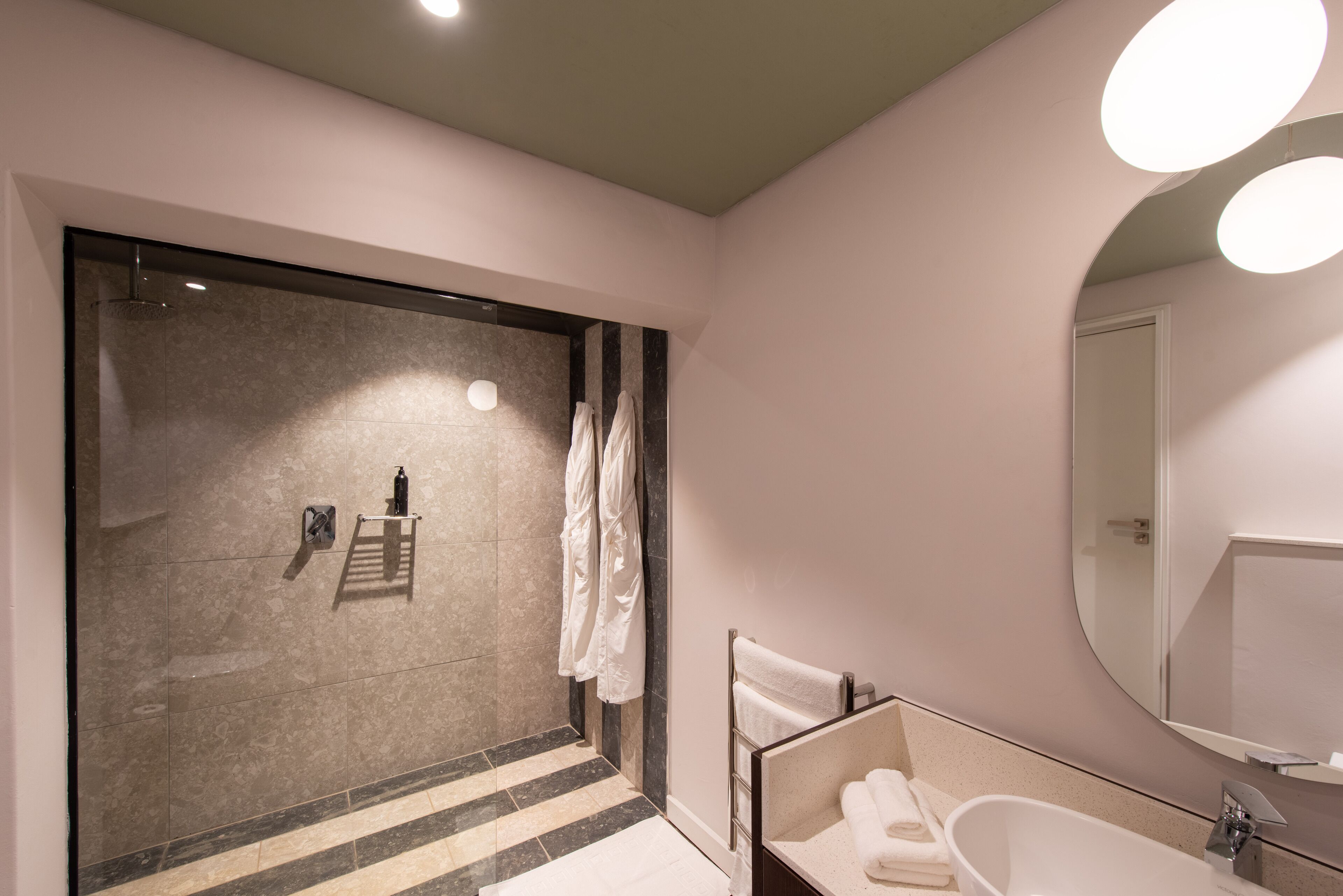 A modern bathroom with a glass-enclosed shower, a vanity with a mirror, and a bathtub.
