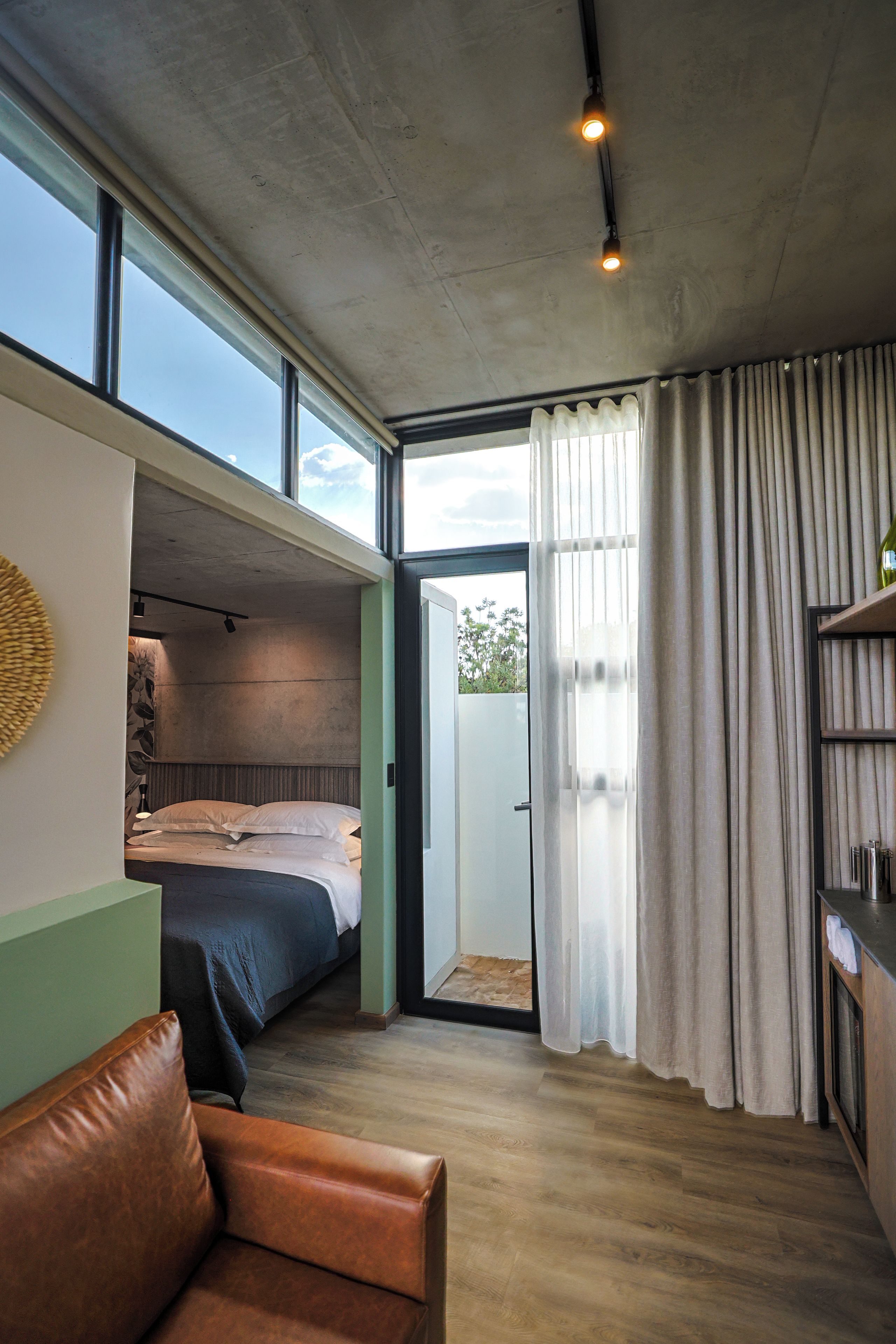 Quarto pequeno com cama, sofá e uma grande janela.
