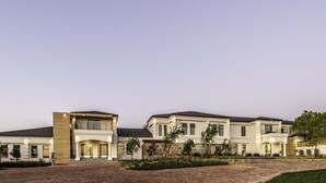 Un grand immeuble résidentiel moderne, doté de plusieurs étages, de grandes fenêtres et d’un jardin paysager bien entretenu.