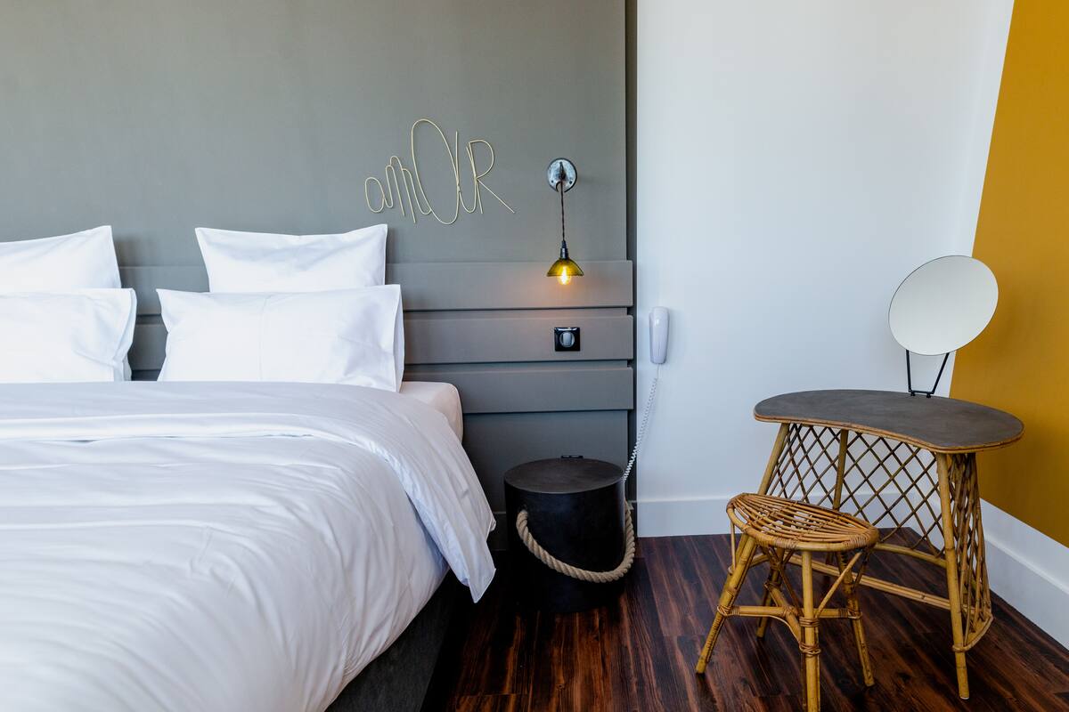 Un dormitorio con cama, mesita de noche, lámpara y una pequeña mesa redonda con una silla.