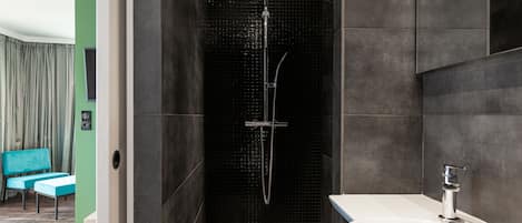 Une salle de bain moderne équipée d’une douche, d’un lavabo et d’un coin salon avec des chaises.
