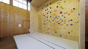 Academia de escalada com paredes de madeira e piso acolchoado.