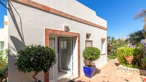 A building with a white exterior, a glass door entrance, and a small window. There are two potted plants in front of the entrance. - Casa Monsoria - sea views, private pool, walking distance to beach & town centre (Carvoeiro)
