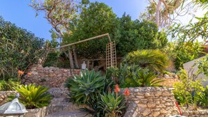 A garden with stone walls, various plants, and a wooden pergola. - Casa Monsoria - sea views, private pool, walking distance to beach & town centre (Carvoeiro)