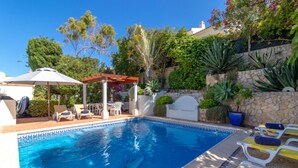 A swimming pool with lounge chairs and a pergola. - Casa Monsoria - sea views, private pool, walking distance to beach & town centre (Carvoeiro)