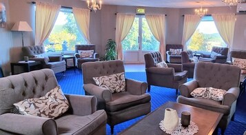 Habitación de hotel con varias zonas de estar, que incluyen sofás y sillones, dispuestas alrededor de una mesa de centro.