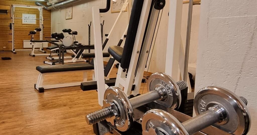 Ein Fitnessstudio mit verschiedenen Trainingsgeräten, darunter Kurzhanteln und Kraftmaschinen.