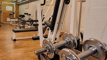 Ein Fitnessstudio mit verschiedenen Trainingsgeräten, darunter Kurzhanteln und Kraftmaschinen.