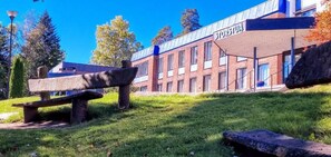 Un edificio con el letrero 'STORSTUA' y un área verde con bancos.