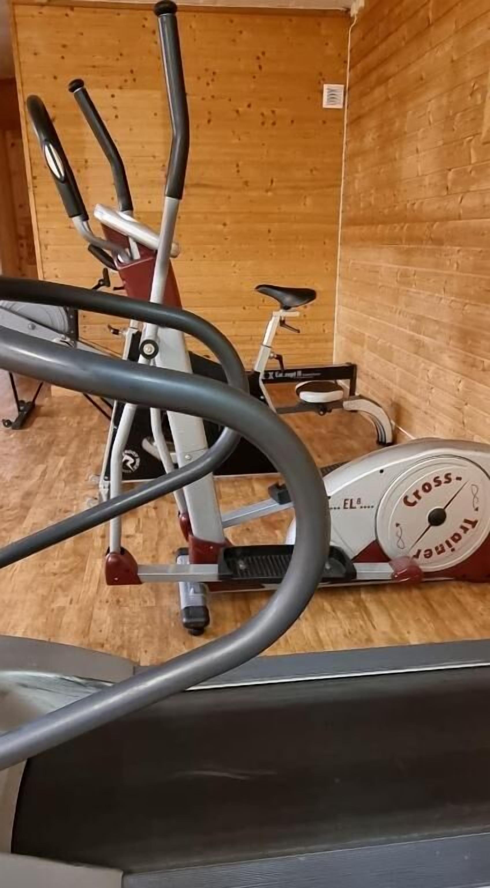 A gym with exercise equipment including a stationary bike and elliptical machine.
