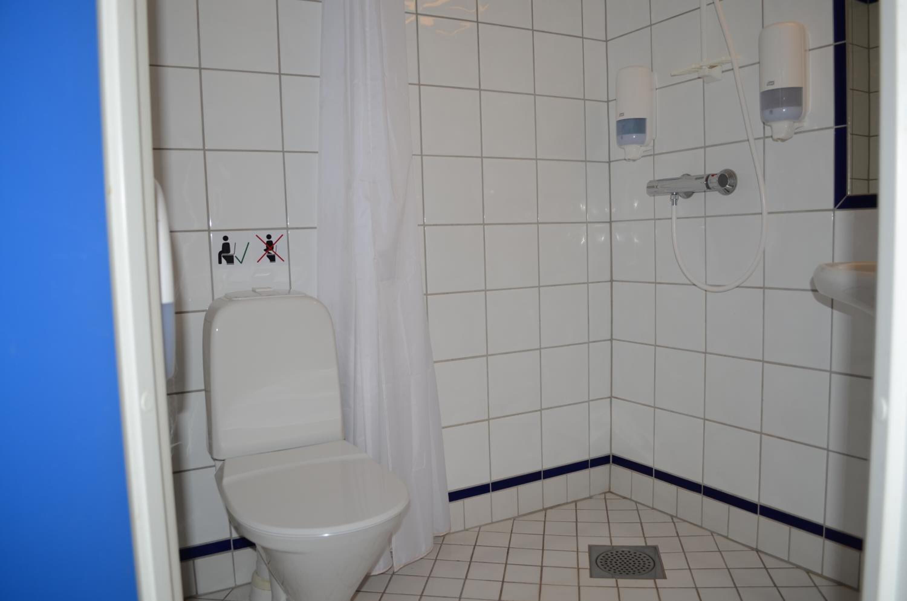 A small, tiled bathroom with a toilet, a shower, and a sink.
