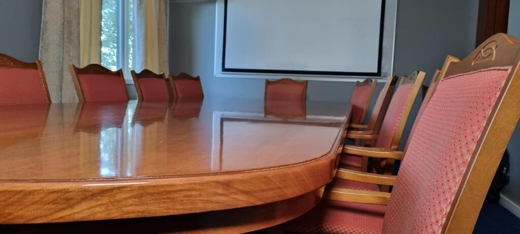A conference room with a round table and wooden chairs.