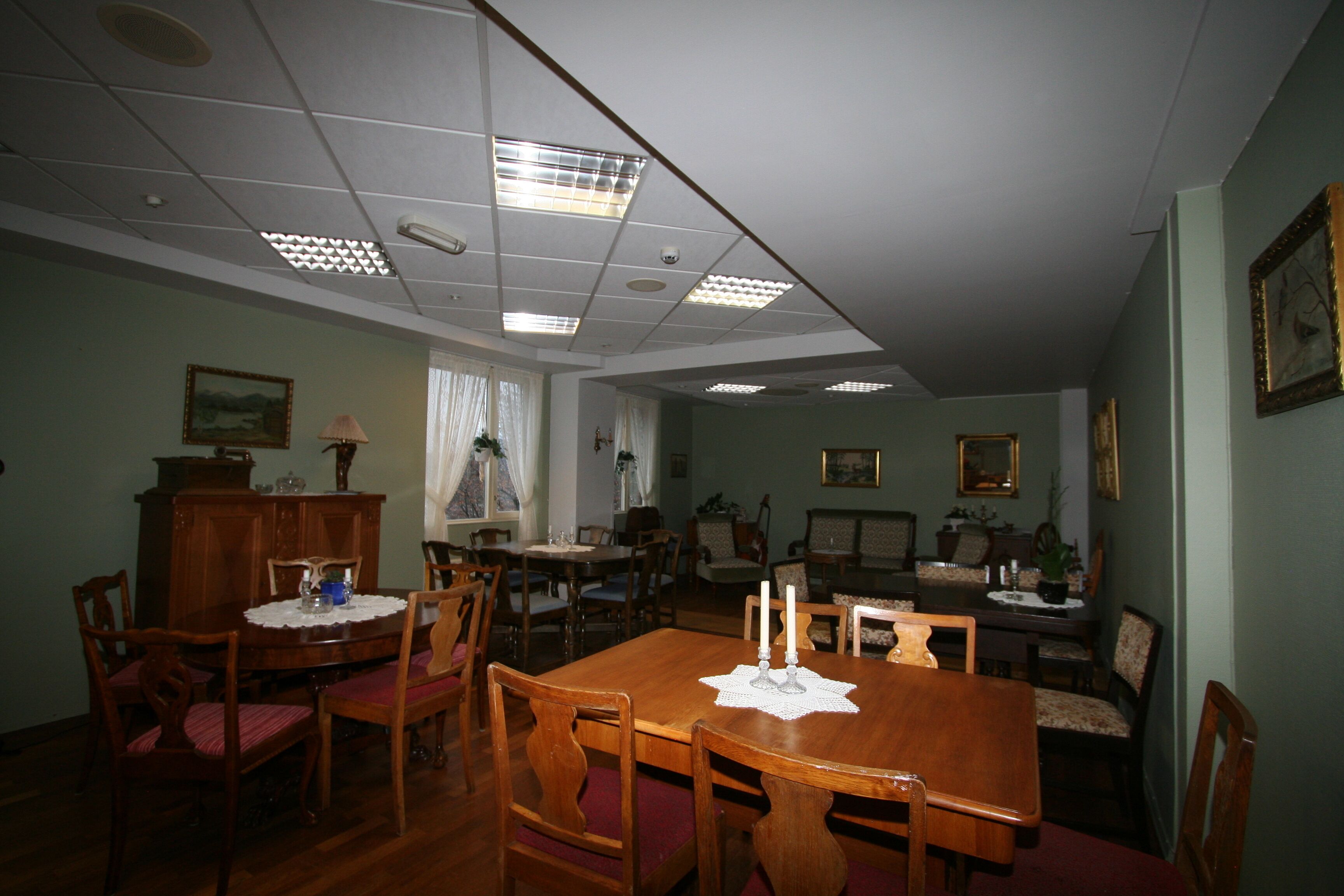 A dining room with a wooden table and chairs, a chandelier, and a ceiling with recessed lighting.