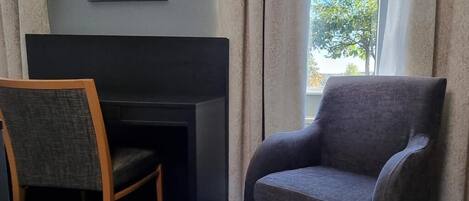 A room with a dark-colored desk, a grey armchair, and a wooden chair.