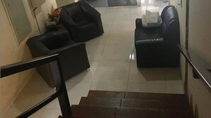 A staircase leading to a lobby area with two black leather sofas and a small table, a glass door entrance, and a tiled floor. - Hotel Brasilia (Buriticupu)