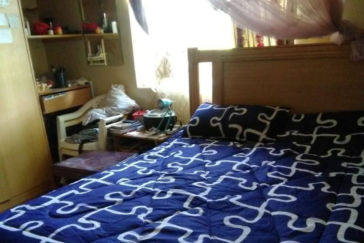 A bedroom with a bed, a desk, and a wardrobe.